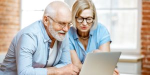 A senior man and woman wearing blue shirts looking at a computer as they research COAs for their CBD products.