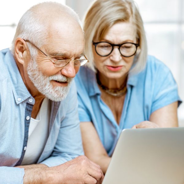 A senior man and woman wearing blue shirts looking at a computer as they research COAs for their CBD products.