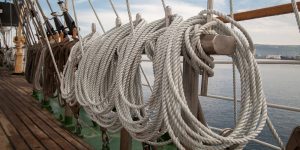 Ropes made from hemp on a ship with the ocean in the background.