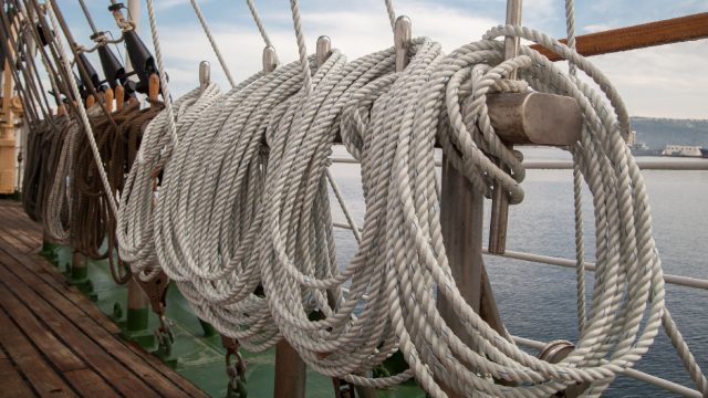 Ropes made from hemp on a ship with the ocean in the background.