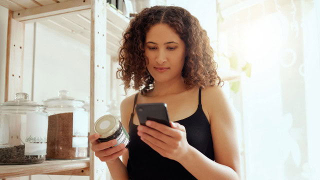 Consumer reviewing a hemp-derived CBD product label and researching product information before purchasing.