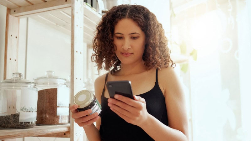 Consumer reviewing a hemp-derived CBD product label and researching product information before purchasing.
