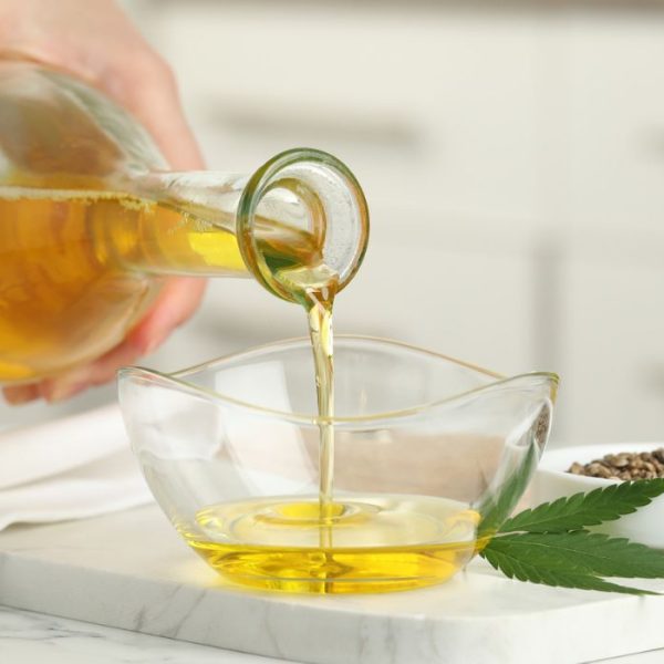 Woman pouring cannabis oil into a glass bowl for cooking