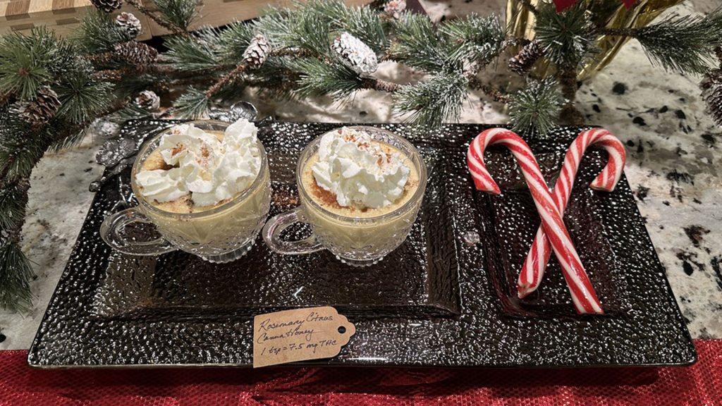 Cannabis-infused eggnog served in glass mugs topped with whipped cream and nutmeg, styled on a festive holiday tray with candy canes.
