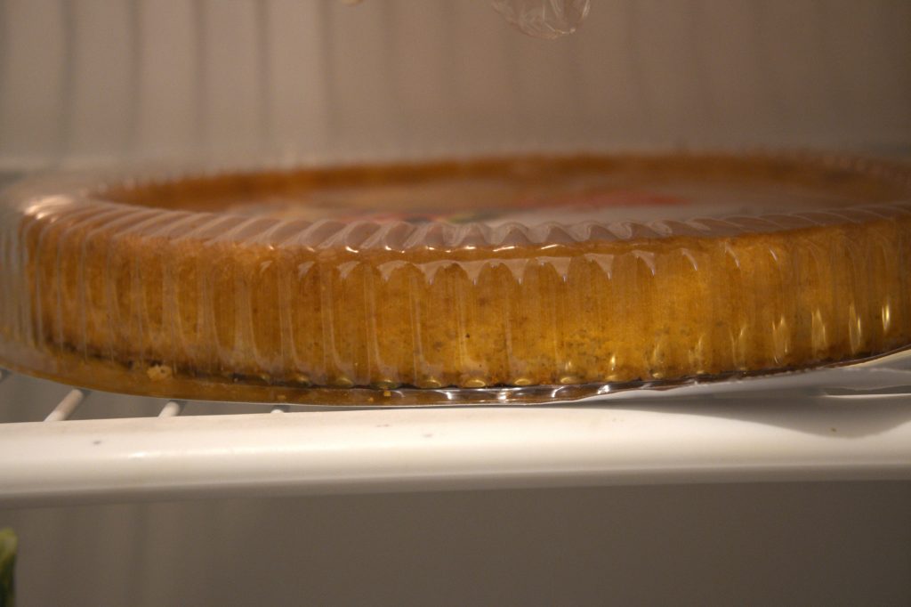 Clear plastic container with cannabis edibles on a cake plate, stored in a refrigerator for freshness and shelf life.