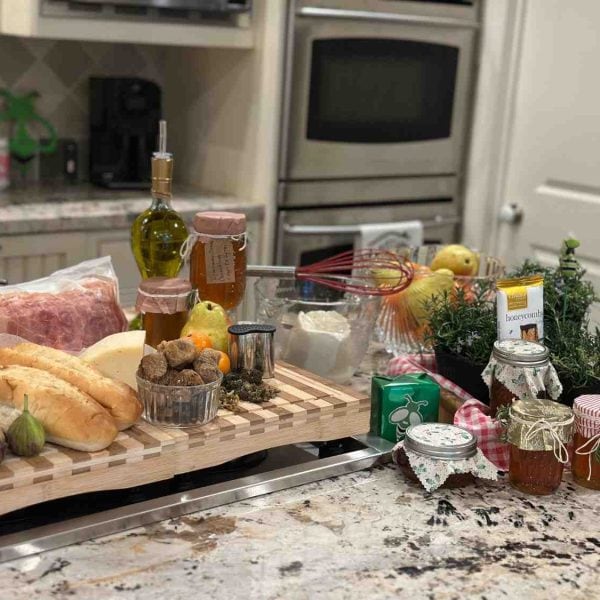 Fresh ingredients for homemade cannabis oil, butter, and honey infusions displayed on a kitchen counter — including olive oil, herbs, honey jars, figs, and citrus.