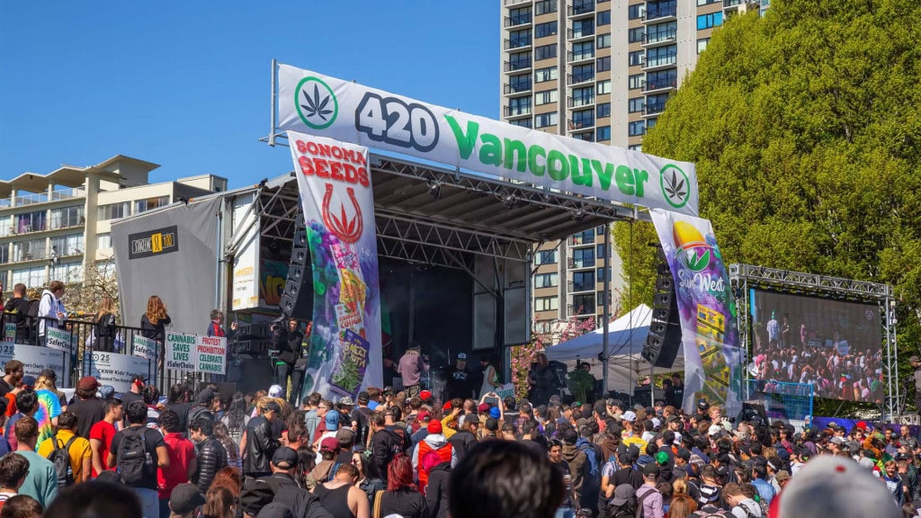 Crowd of people are gathered to celebrate 420 at Sunset Beach during a sunny day.