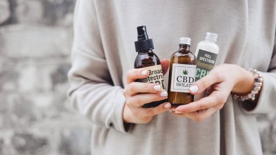 Consumer holding CBD product labels and hemp-derived wellness products.