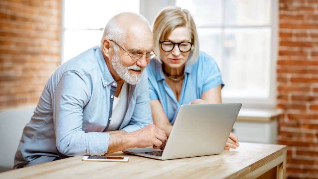 Older couple reviewing a Certificate of Analysis (COA) and cannabis product information on a laptop before making a purchase.